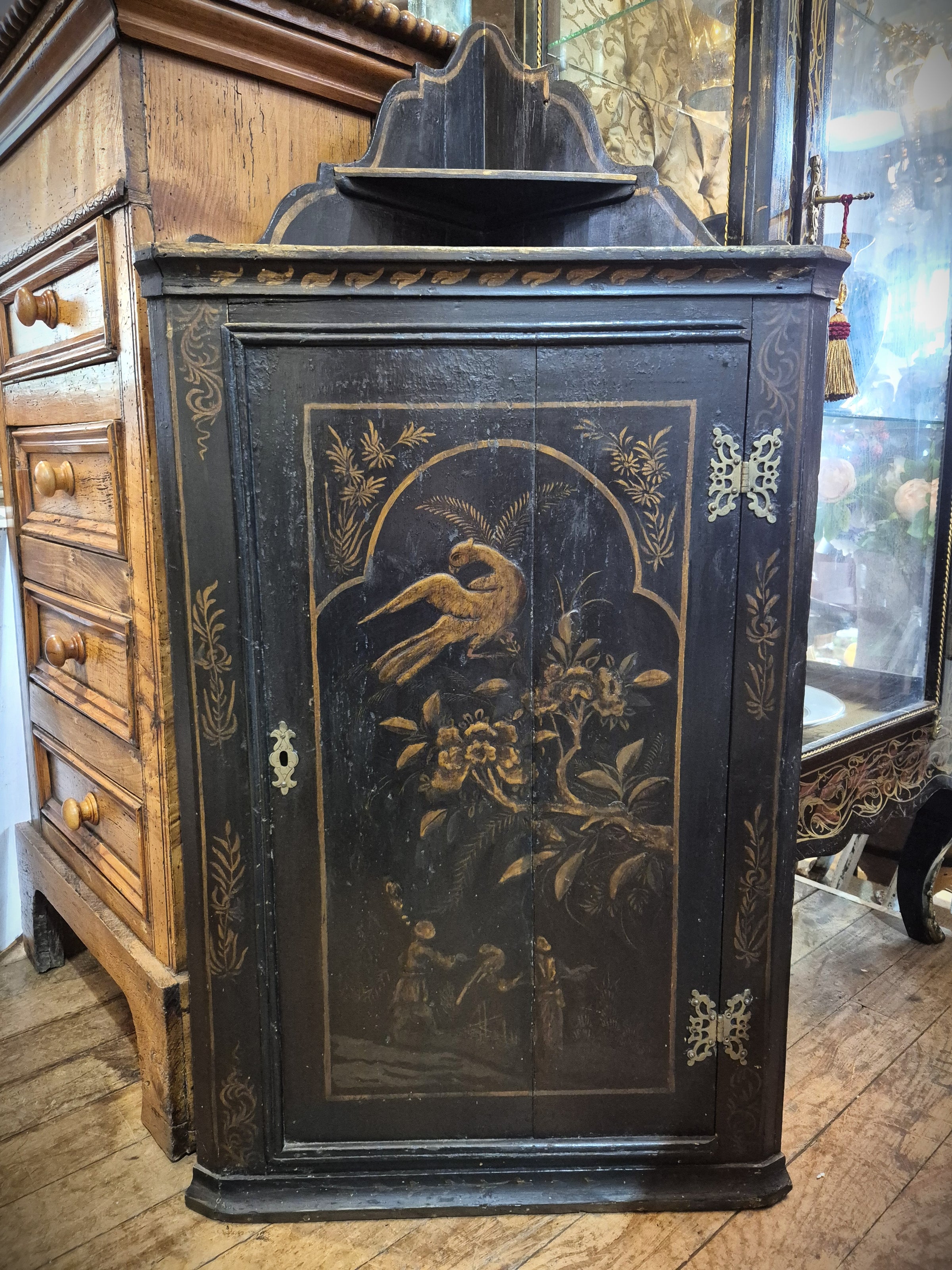 Decorative antique black Chinese corner cabinet with floral and bird design painted in gold.