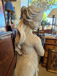 Statue of a woman in an interior setting with furniture and decor.