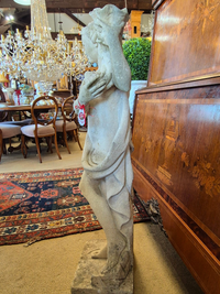 Statue of a nude figure in an antiques store with chandelier and furniture in the background