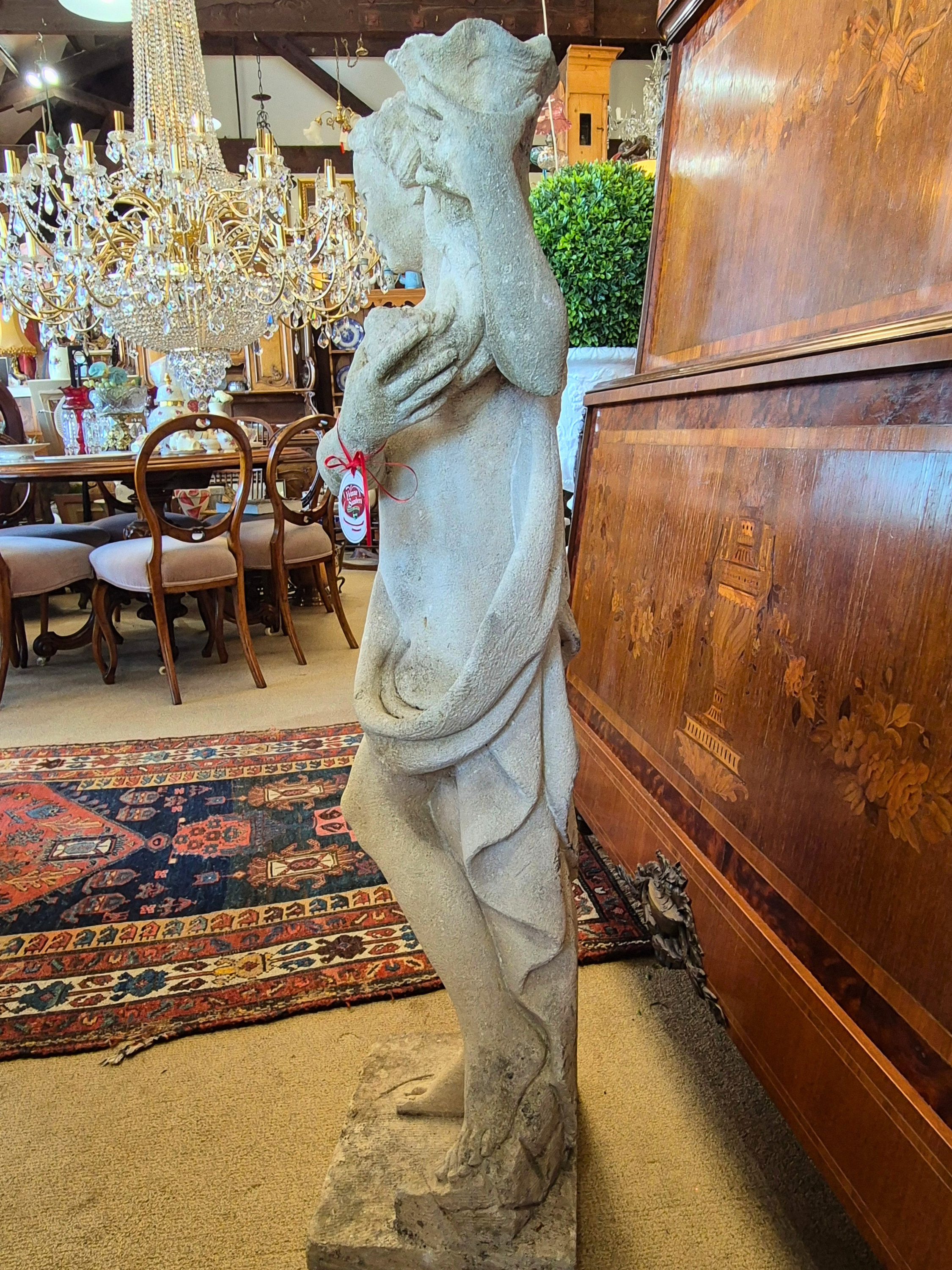 Statue of a nude figure in an antiques store with chandelier and furniture in the background