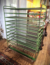 A green metal wire rack cart with multiple tiers, photographed in Yvonne Sanders Antiques shop.