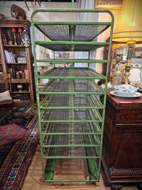 A vintage green metal bakers rack, showing the side view with 10 wire racks.  