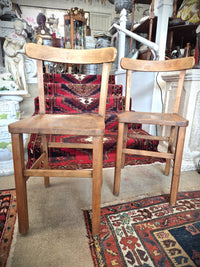 Pair of wooden childrens school chairs on a patterned rug with decorative items in the background
