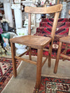 Wooden childs school chair on a patterned rug with decorative items in the background