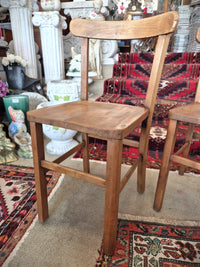 Wooden childs school chair on a patterned rug with decorative items in the background