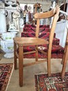 Wooden childs school chair on a patterned rug with decorative items in the background side view