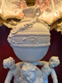 Decorative lamp with cherub figures on a dark background
