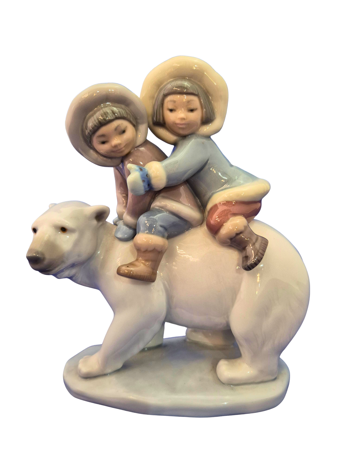 A ceramic figurine of two children riding a polar bear, shown against a plain white background.