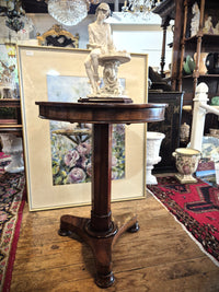 Mahogany wine table showing a figurine atop.
