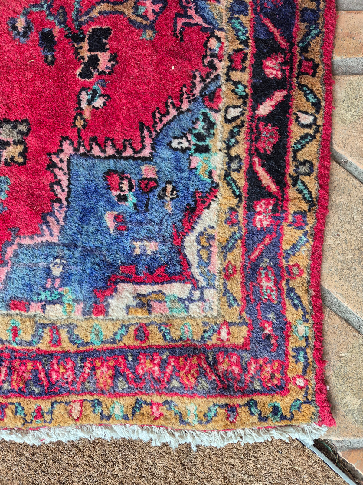 Close-up of a colorful Persian rug corner on a textured surface