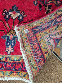 Close-up of a patterned rug with visible brand label on a textured surface