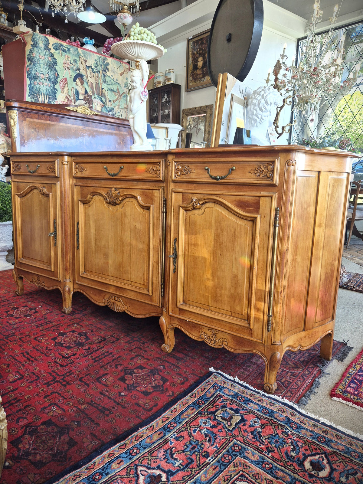 An antique French-style wooden sideboard cabinet with carved details and brass hardware.