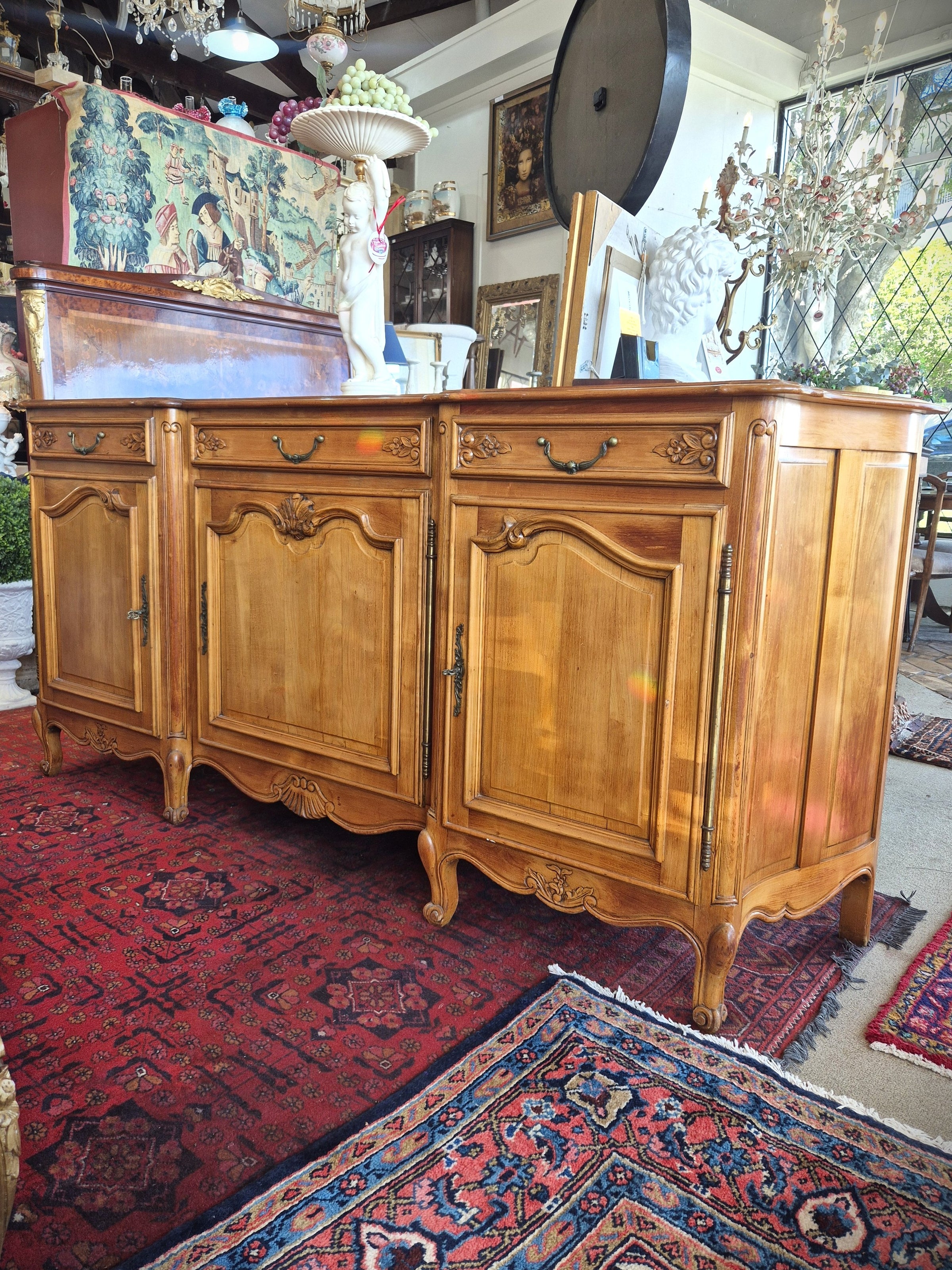 An antique French-style wooden sideboard cabinet with carved details and brass hardware.